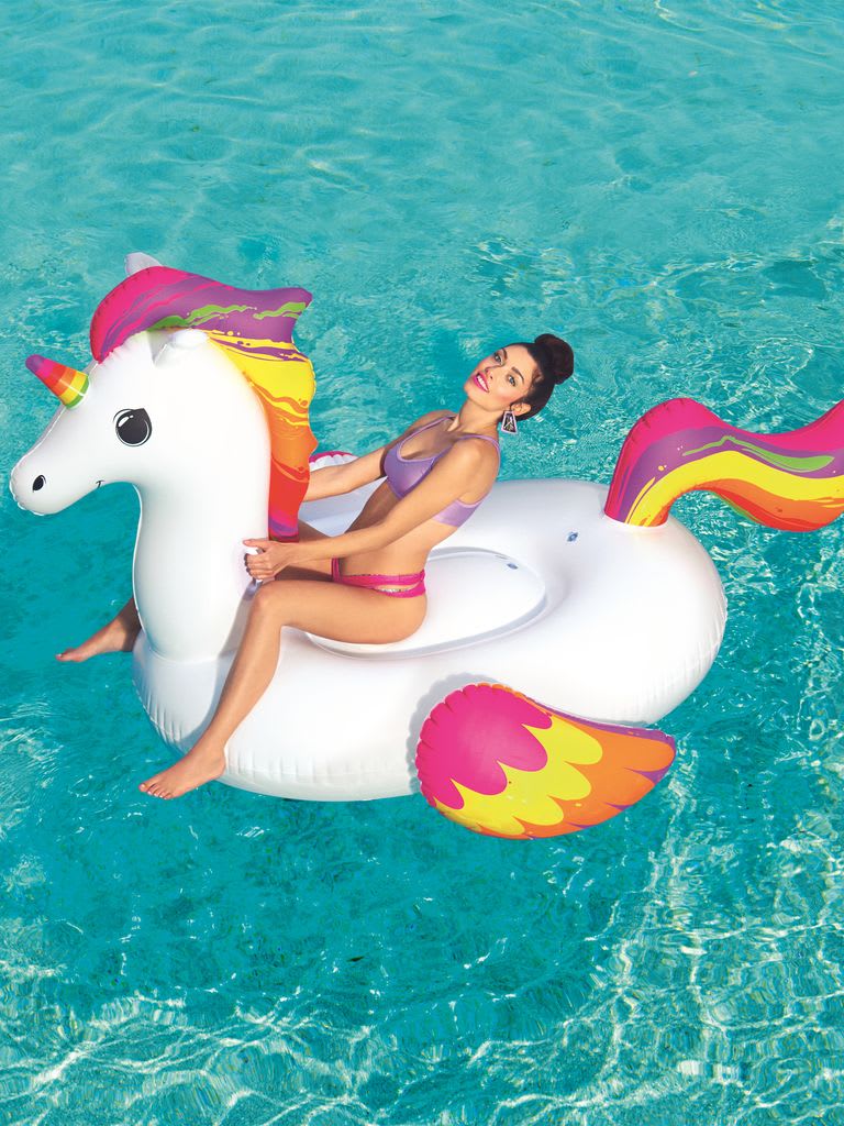 Woman on a unicorn-shaped inflatable pool float in clear blue water