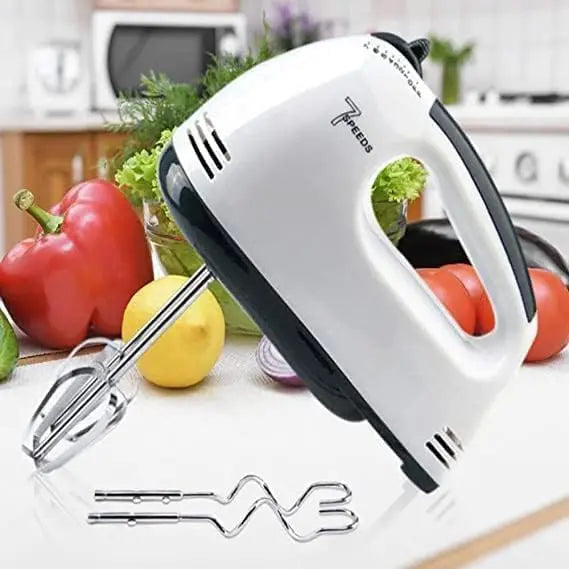 Hand mixer on a kitchen counter with vegetables in the background