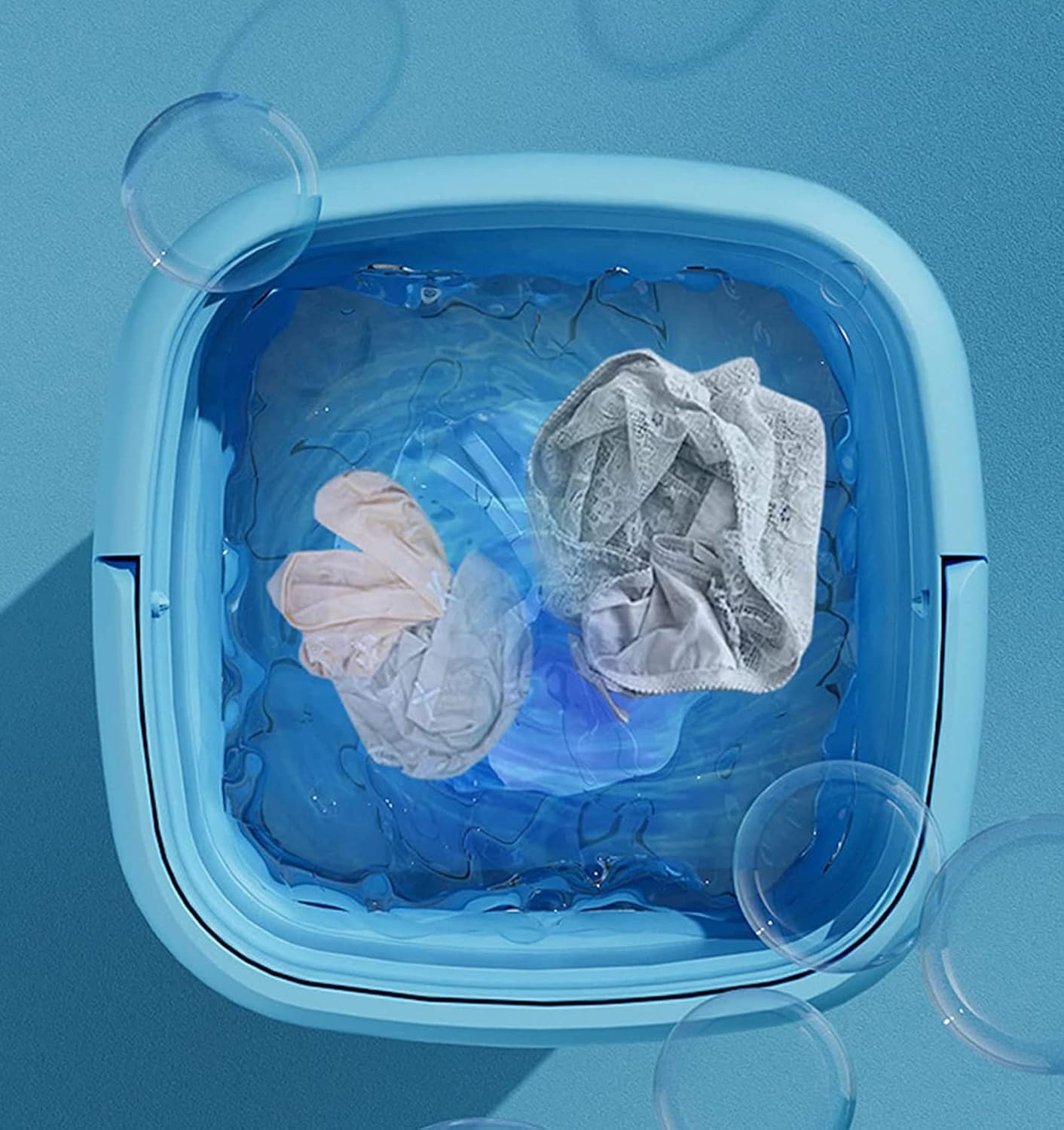 Washing machine with clothes and water on a blue background