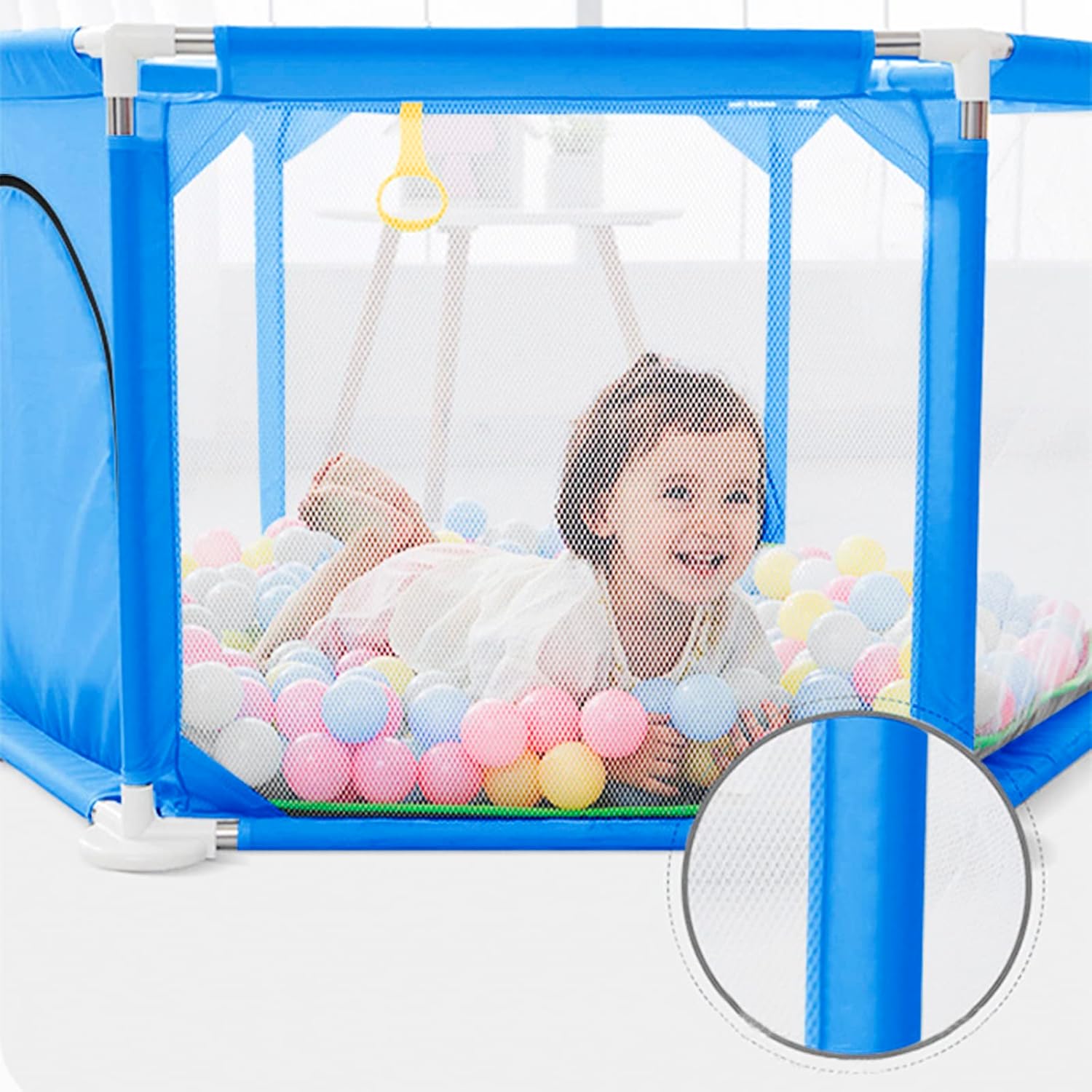 Child playing inside a blue playpen with colorful ball pit