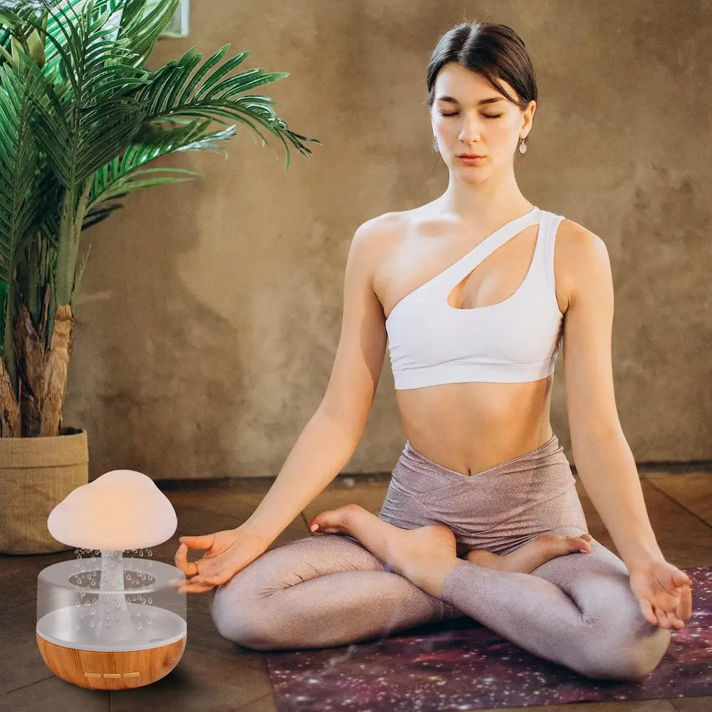 Woman meditating on a yoga mat with a diffuser in front of her