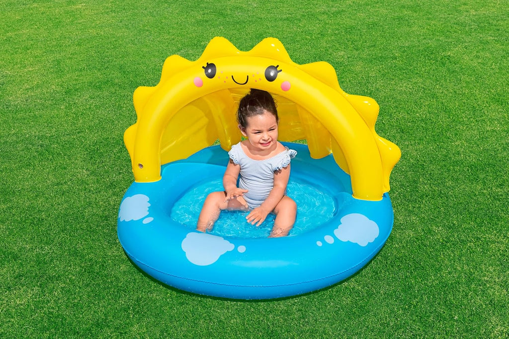 Child sitting in a yellow inflatable sun-shaped pool on a grassy background