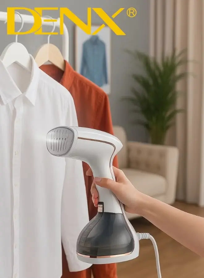 Hand holding a Denx garment steamer over a white shirt and brown jacket on hangers.