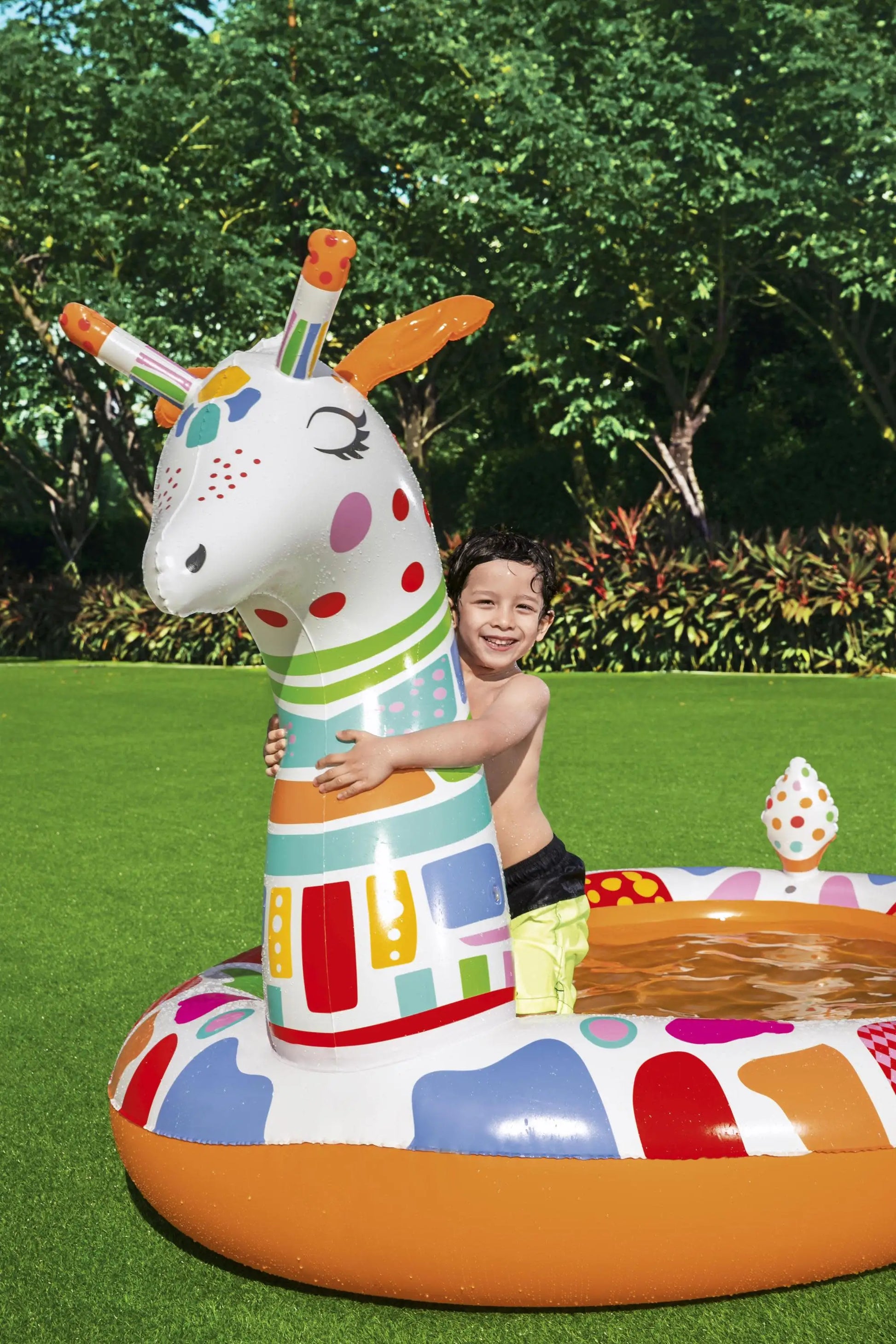 Child playing with a colorful inflatable giraffe pool toy on grass