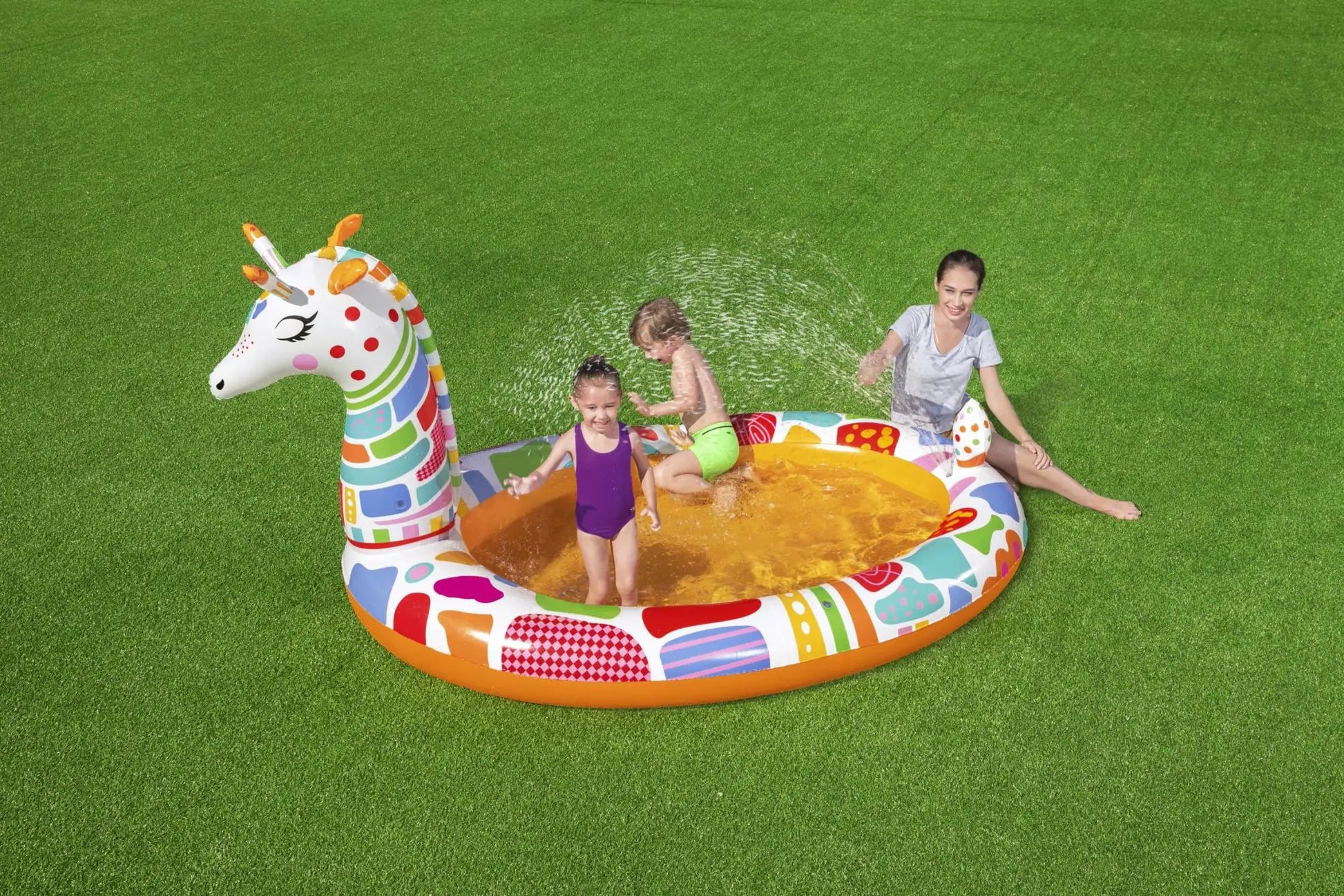 Children playing on a colorful inflatable pool toy shaped like a dragon on grass.